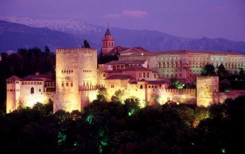 La Alhambra de Granada iluminada por la noche con Sierra Nevada al fondo